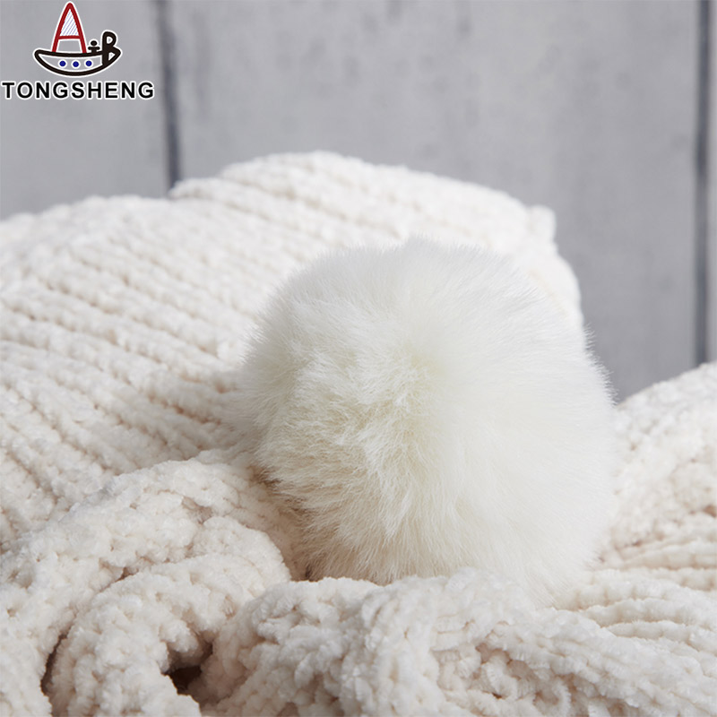 The pom poms of the white knitted blanket look very comfortable